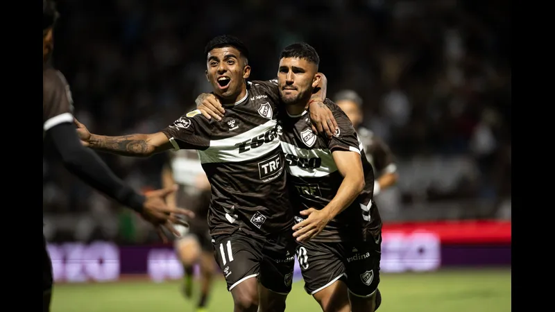 Cầu thủ của Platense đang nỗ lực vượt qua phòng ngự của Deportivo Riestra trong trận đấu. Cầu thủ của Platense đang nỗ lực vượt qua phòng ngự của Deportivo Riestra trong trận đấu.